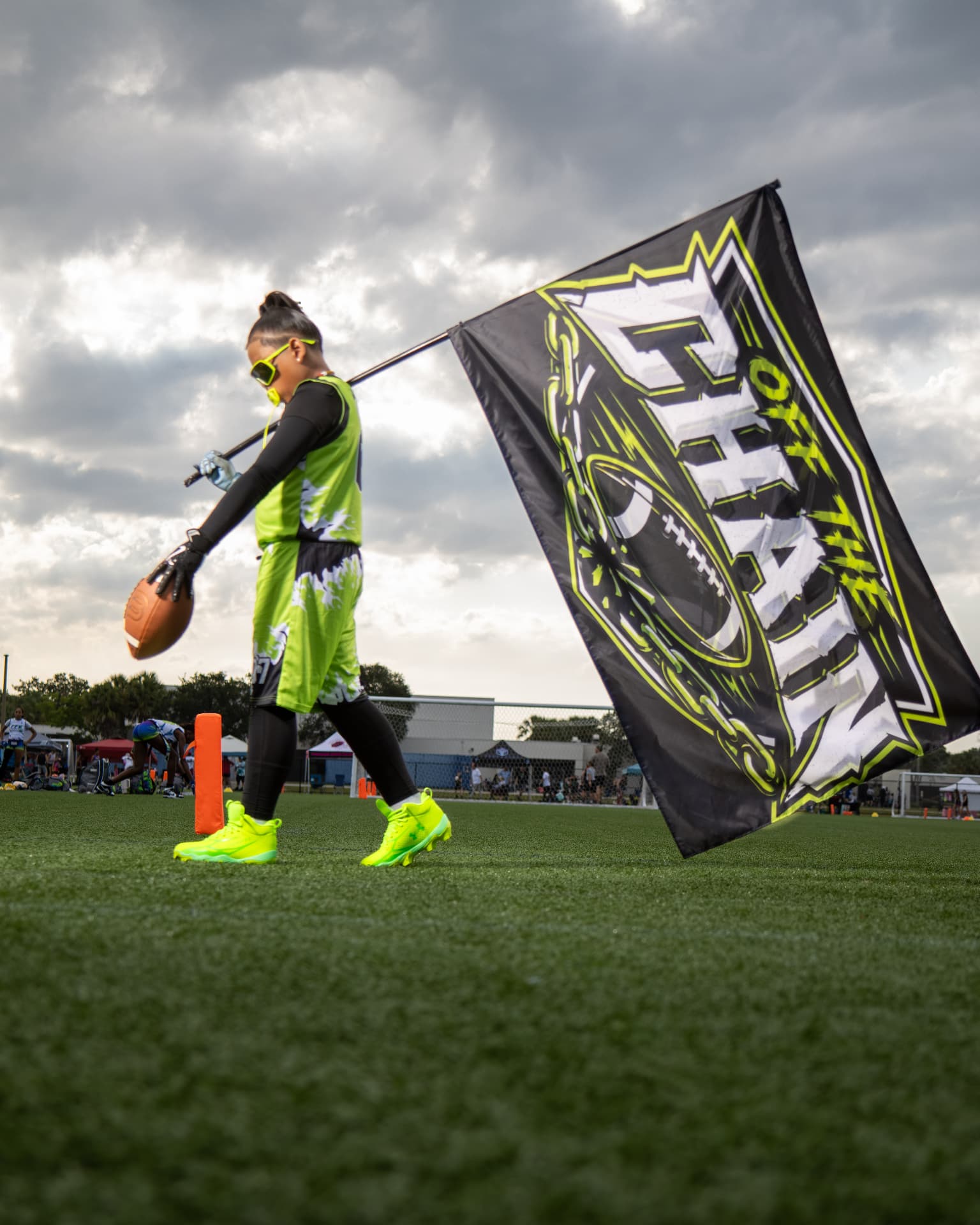 Off The Chain Performance youth flag football player carrying the team flag, Orlando, Central Florida